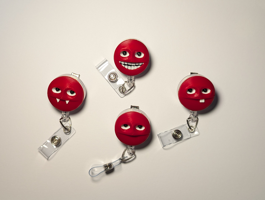 Four red retractable badge reel clips with cartoon face details, arranged on a light gray background.